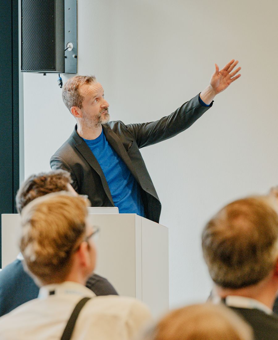 Heiko Bartlog hält einen Impulsvortrag, Arm im Schwung erhoben, vor Publikum.